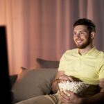happy man with popcorn watching tv at night