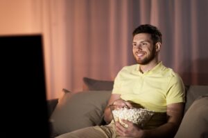 happy man with popcorn watching tv at night